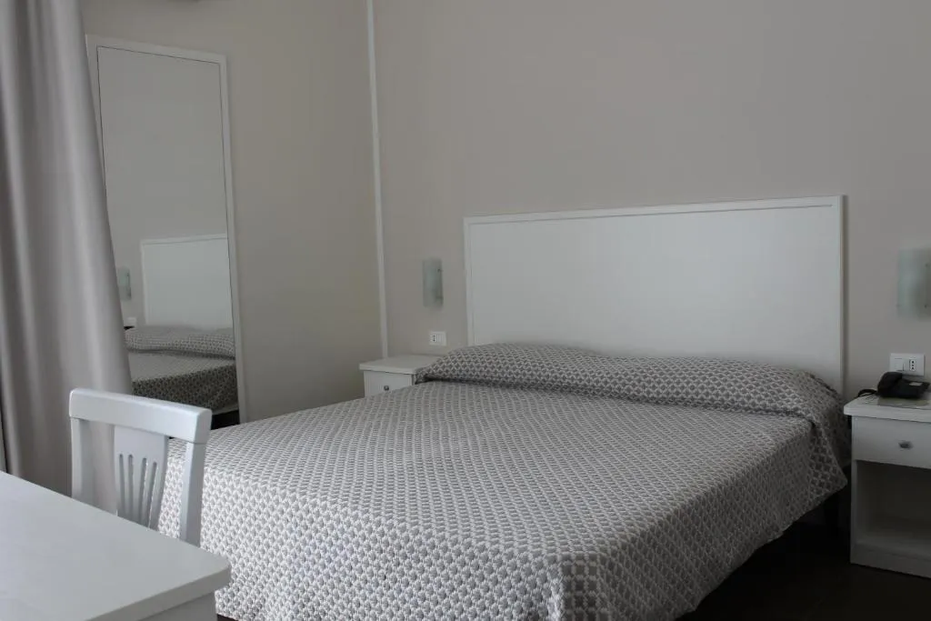 Camera matrimoniale bianca con letto, specchio e comodini