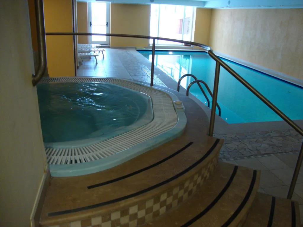 Piscina coperta con vasca idromassaggio e scalinata in marmo