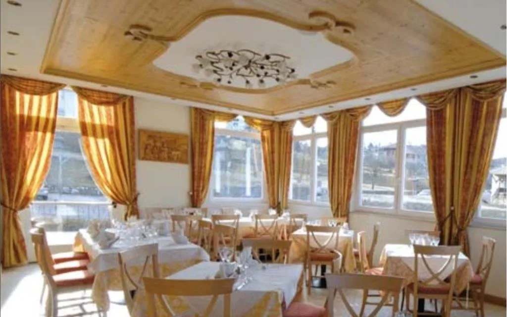 Sala ristorante luminosa con tende dorate e tavoli apparecchiati